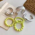 Collection of chunky silver bangles and yellow beaded bracelets displayed on an open book - 6-Piece Set / 63# Bangle Silver Cyan
