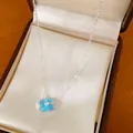 Macro detail of a silver-toned four-leaf clover necklace with blue resin and zircons - Silver-Blue