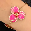 Elegante pulsera dorada con un vibrante amuleto de flor de esmalte rosa en la muñeca - Pulsera (11516) / Rosa oscuro