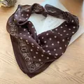Detailed view of brown paisley pattern on a retro square silk scarf on a book. - Coffee Flower