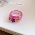 Macrodetail van dopamine roze harsring met kleurrijke vierkant geslepen strass-steentjes - Zetting met drie diamanten / Roze-Paars
