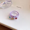 Detailopname van paarse harsring met ingebedde gekleurde strassteentjes luxe - Zetting met drie diamanten / Paars En Bruin