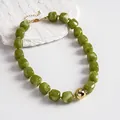 Close-up of olive green marbled acrylic beads and gold sphere on a retro geometric necklace. - Necklace / Gold-Green