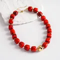 Close-up of retro red marbled acrylic beads and gold sphere on a geometric necklace - Necklace / Gold-Red