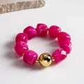 Close-up of fuchsia marbled acrylic bead bracelet with a large gold metal sphere - Bracelet / Gold-Rose Red