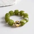 Detail view of vintage olive green marbled acrylic beads with a reflective gold sphere focal point - Bracelet / Gold-Green
