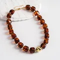Close-up of vintage amber acrylic necklace with chunky gold central bead detail - Necklace / Gold Brown