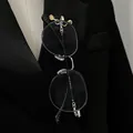 Detailed close-up view of the CD logo brooch holding black glasses on a black suit lapel - 02 Kc Gold A-1155 (glasses Not Included)