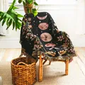 Manta tejida con fases lunares y flores sobre una silla de mimbre en una habitación acogedora - Fases Lunares Floral - Negro / 130x160cm
