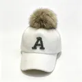 Close-up of white furry baseball cap with rhinestone letter A and brown fur pom-pom detail. - Adult 58cm Adjustable / Rhinestone Letter A & Raccoon Fur Pom-pom Style / White