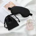 Elegant black silk-like sleep mask and drawstring pouch set on white fabric background - Black