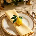 Elegant yellow lemon napkin ring featuring green leaves placed on a yellow cloth napkin - Lemon with Large Leaf