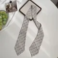 Detailaufnahme eines Satin-Schals mit Leopardenmuster auf einem sauberen weißen Schreibtisch - Schwarz Beige Buchstabendruck