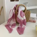 Detail eines rosa-weiß gemusterten Seidenschals, der über eine Korbtasche drapiert ist. - Rosa Weiß Geometrisch Gepunktet