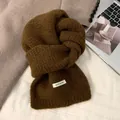 Detaillierte Nahaufnahme eines braun gestrickten Wollschals mit weicher Textur und Etikett - Braune Wollmischung