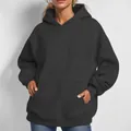Close-up detail of women's oversized black hoodie featuring kangaroo pocket and hood. - Black