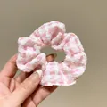 Süßer pink-weißer Gingham Haargummi für den Pferdeschwanz, in der Hand präsentiert - Karo-Stil / Rosa