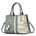 Primer plano del bordado floral y los herrajes dorados de este elegante bolso verde - 31x14x22cm / Verde