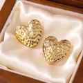 Close-up view of golden quilted heart-shaped earrings in a satin-lined gift box - Twisted Heart