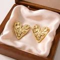 Macro shot of textured gold-tone heart stud earrings in a wooden gift box - Heart Biscuit