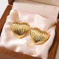Close-up detail of vintage style gold ribbed heart stud earrings displayed on cream silk - Ridged Heart Earrings