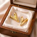 Macro view of polished gold heart-shaped stud earrings resting in a wooden jewelry gift box - Elongated Heart Earrings