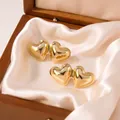 Exquisite macro detail of polished gold double heart stud earrings on soft cream satin - Double Heart