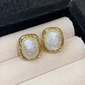 Elegant gold-plated stud earrings featuring oval imitation star pearls in a textured frame - 64 Silver Needles - Gold - White