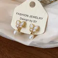 Elegant gold-plated butterfly stud earrings featuring white pearl drops and zircon accents - 7 Ear Clips - Gold