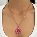 Elegant double-layered gold-tone necklace with a pink flower pendant on a model - Double Layer Ocean Style Flower (N-1139)