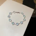 Elegante bracciale argentato con zirconi azzurri quadrati in una montatura halo floreale - Bracciale / Argento-Blu