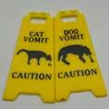Humorous yellow plastic folding caution sign featuring cat and dog vomit warnings - Yellow Dog and Cat Sign Set