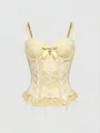 Close-up detail of a cream lace corset tank top with a cross charm and ribbon lacing - Yellow