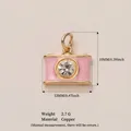 Elegante ciondolo a forma di fotocamera rosa con strass e misure indicate su sfondo neutro - Ciondolo Fotocamera Rosa
