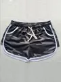 Detailed close-up view of women's camouflage drawstring sports shorts with white trim - M / Bottoms / Grey Camouflage