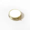 Primer plano de un pastillero redondo de metal vintage con tapa blanca - Interruptor de presión / Redondo Liso / 50mm / Dorado