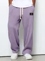 Nahaufnahme der lila Waffelstrick-Herrenhose mit dekorativem schwarzem Etiketten-Patch. - Lila / S