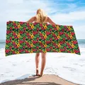 Model holding a microfiber beach towel with a vibrant tropical floral pattern on a beach. - 75x150cm / Floral Style