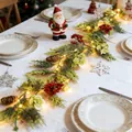 Detailaufnahme einer festlichen LED-Weihnachtsgirlande mit Beeren und Zapfen auf Tisch - Künstliche Eukalyptus-Zypressenzweig Stil / Beutelverpackung