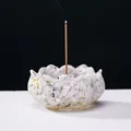 Lotus-shaped natural white crystal incense holder with gold leaf flakes and burning incense - Howlite Lotus Base