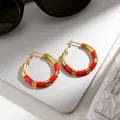 Primer plano detallado de pendientes de aro de acero inoxidable rojo y dorado en portátil - Rojo