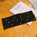 Fascia per capelli in tessuto nero con stelle argentate e strass su un libro decor. - Nero