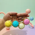 Detailaanzicht van een hand die vier kleurrijke lichtgevende sleutelhangers vasthoudt - Zonder Expressie / Doosverpakking / Geel (Eenvoudig)