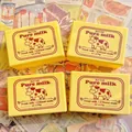 Butter-Squishy-Spielzeug mit Vintage-Vollmilch-Kuh-Etikett auf einem Magazin-Hintergrund - Milchbutterblock [10cm]