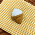 Close-up detail of a soft simulation flour ice cream squishy toy on yellow checkered cloth - White