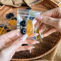 Close-up view of mini fruit squishy bag featuring simulated blueberry and orange slice - 1 Orange Segment And 2 Blueberries / 3-Pack