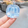 Detail view of a blue iridescent Canelé-shaped stress relief squishy toy held by hand. - Canelé Shaped / PVC / Glacier Blue