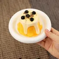 Gedetailleerde close-up van een realistische pudding knijpspeeltje met room op een wit bord - Parelpudding Stijl / Teder Geel