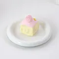 Gros plan détaillé du jouet squishy gâteau aux fraises rose sur une assiette blanche. - Squishy Élastique Coloré / Rose