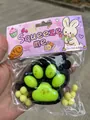 Detailansicht eines 7 cm großen Katzenpfoten-Quetschspielzeugs in einer Geschenkverpackung - 7cm Groß (Mit Glitzer und Pailletten) / Schwarz-grüne Katzenpfoten-leuchttafel